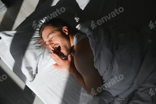 Preview: Happy young bearded man is relaxing on the bed at home