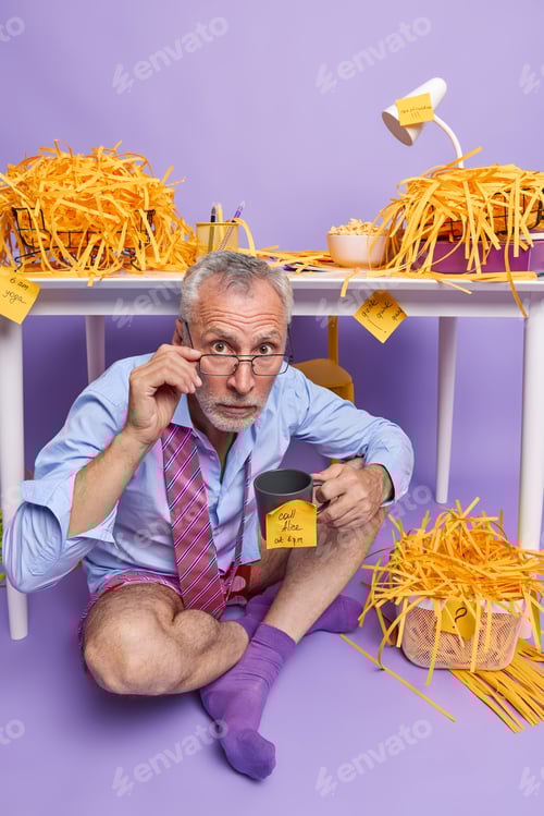 Preview: Indoor shot of grey haired businessman wears formal shirt and tie over neck works remotely at cozy h