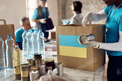 Preview: Close-up of food bank volunteer packing donation boxes for Ukrainian people in need.