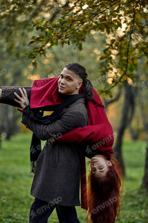 Preview: Young couple in love walking in the autumn park holding hands looking in the sunset