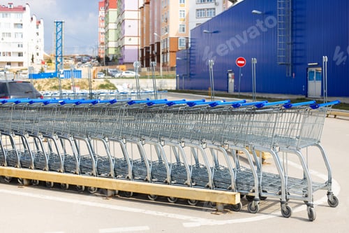 Preview: Many empty blue metal carts for shopping in a supermarket parking
