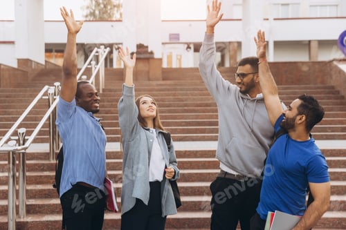 Preview: Diverse Group of Happy University Students Celebrating Together on Campus Steps with Raised Hands