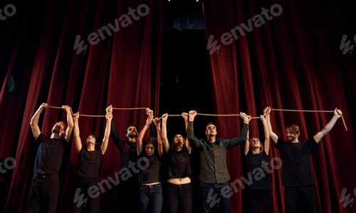 Preview: Group of actors in dark colored clothes on rehearsal in the theater