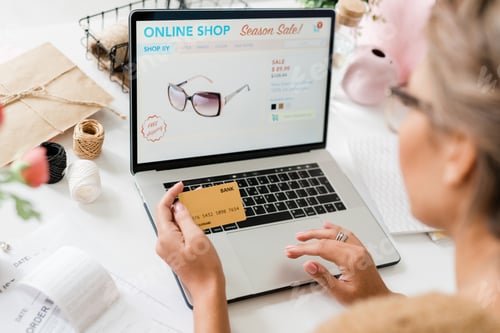 Preview: Model of stylish eyeglasses on laptop display and hands of young female shopper