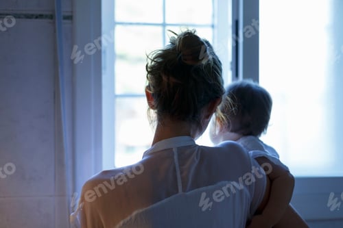 Preview: Rear view of mid adult woman and baby daughter looking out of living room window