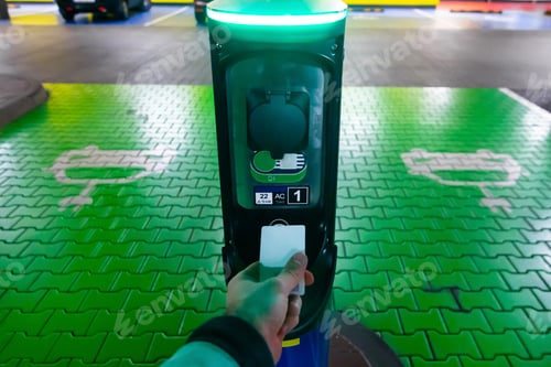Preview: A man pays for charging an electric car. Hand holding catd to pay at charging station. Concept of