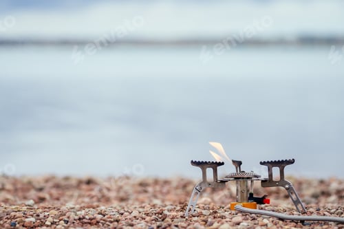 Preview: The pan with the porridge stands on the gas burner (Camping Stove). On the background of the river