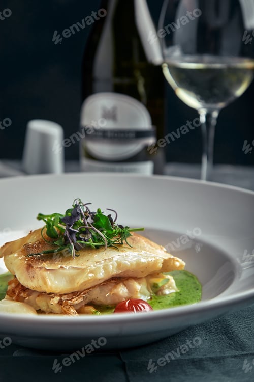 Preview: White steak of grilled fish on pillow of vegetables and yellow sauce, with tomatoes and fresh herbs