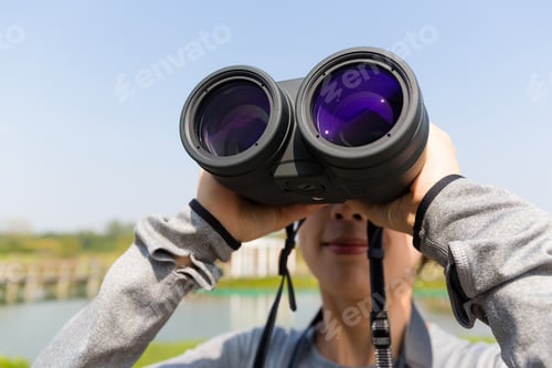 Preview: Adult Looks Through Binoculars Outdoors on a Sunny Day