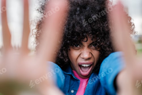 Preview: Curly-haired woman screaming at the camera and covering it with her hands