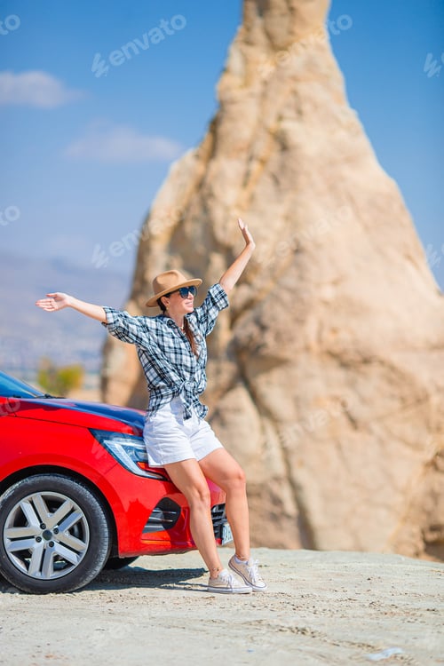 Preview: Young happy woman on vacation by car in Cappadocia. Cave formations.