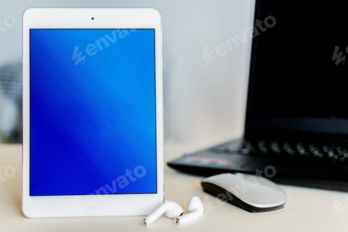 Preview: Tablet with blue screen next to a laptop on a desk - technology and business concept