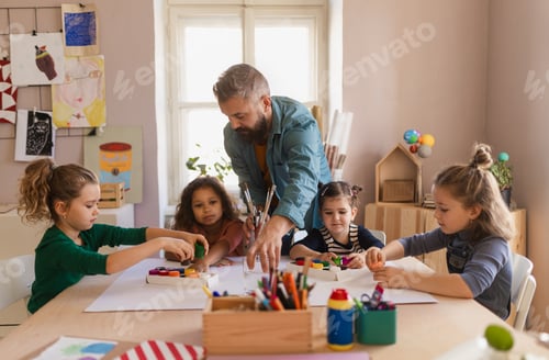 Preview: Group of little kids working on project with teacher during creative art and craft class at school