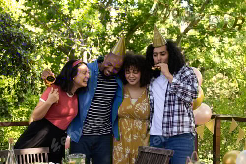 Preview: Celebrating outdoors, friends wearing party hats and smiling in festive atmosphere