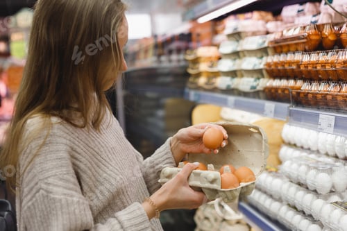 Preview: Woman chooses chicken eggs in a farm food store. Food consumption, Easter