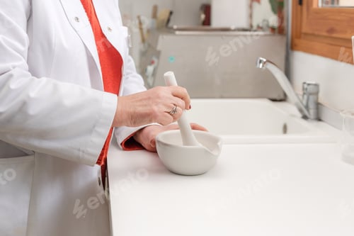 Preview: Close up of female Pharmacist preparing medication with mortar and pestle in pharmacy laboratory