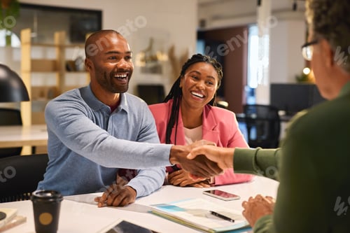 Preview: Businessman shaking hands with couple after deal