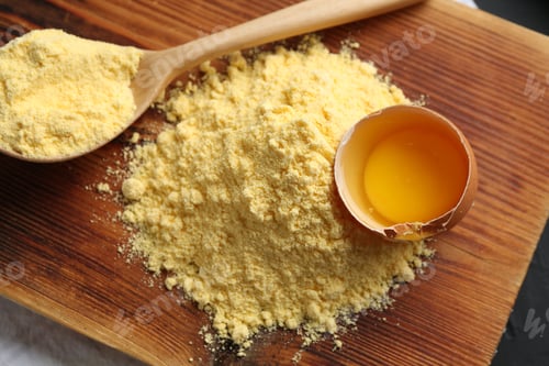Preview: Pile of corn flour, spoon and broken egg on table, top view