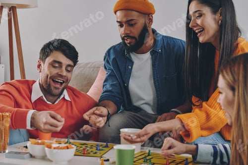 Preview: Happy young people playing board game while enjoying carefree time together