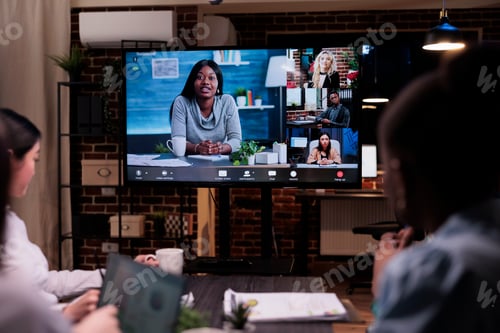 Preview: Selective focus on tv screen with online video conference in startup office with mixed team in late