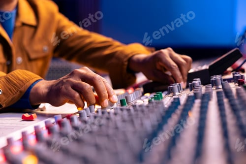 Preview: African american sound engineer twisting knobs to edit music in studio,