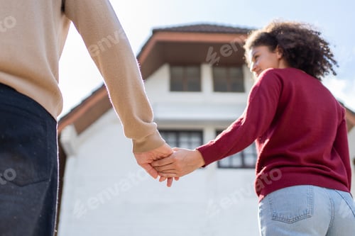 Preview: Close up of Latino young couple walking in front of their new house.