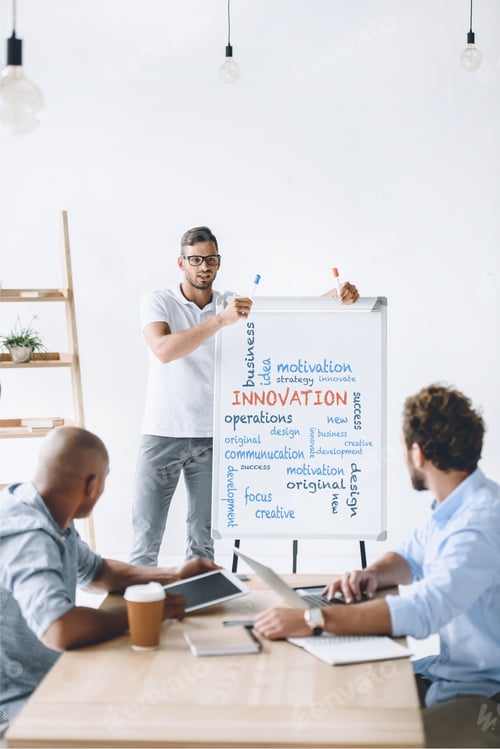 Preview: young businessman at white board making presentation to colleagues