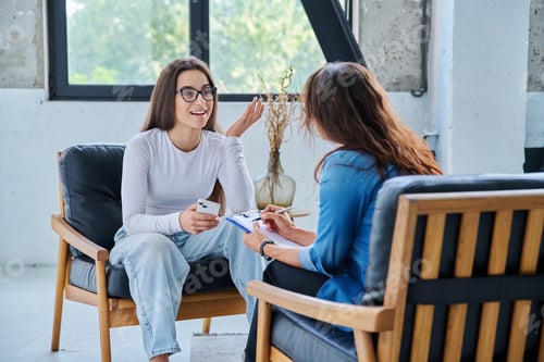 Preview: Young smiling girl patient in therapy session with social mental therapist
