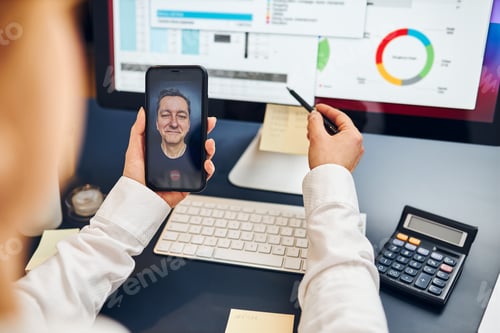 Preview: Woman entrepreneur having business video chat on smartphone with her business partner. Office work