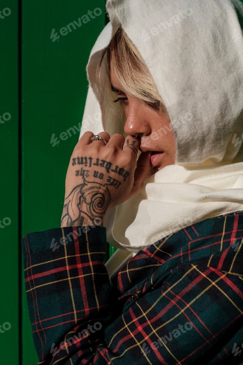Preview: Pensive young alternative woman is wearing a scarf on her head.