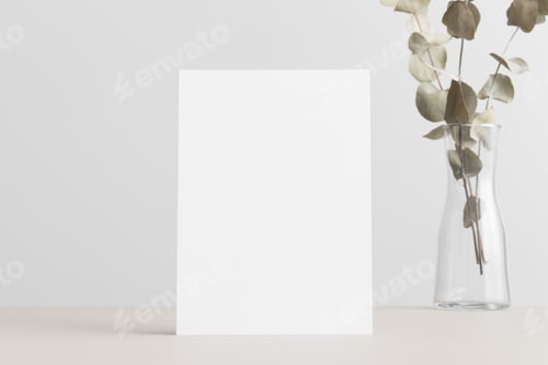 Preview: White invitation card mockup with an eucalyptus on a beige table. 5x7 ratio, similar to A6, A5.