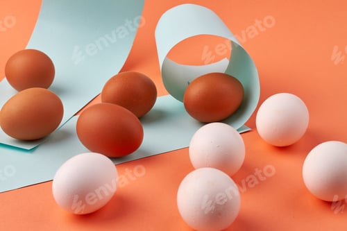 Preview: White and brown chicken eggs and paper pieces.