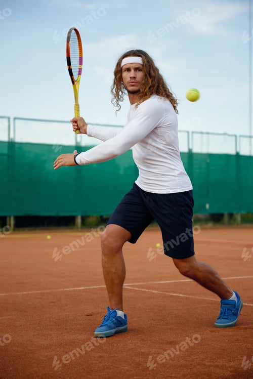 Preview: Sportsman hitting ball with tennis racket playing on open court in summer