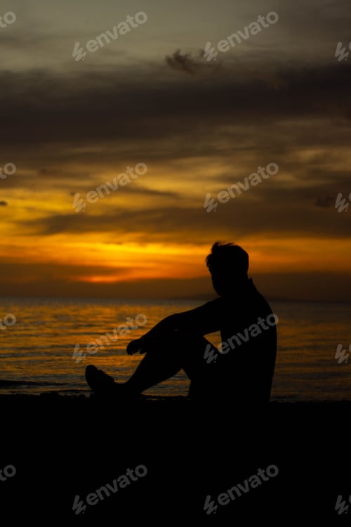 Preview: Young adult male silhouette featured in a beach setting at sunset