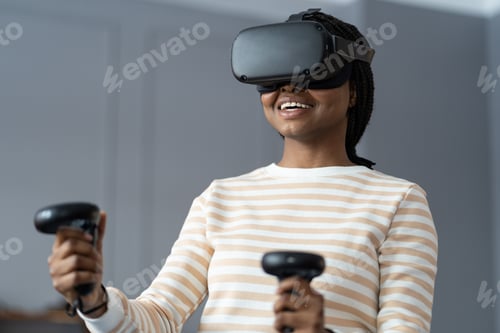 Preview: Happy young African woman playing VR games, enjoying gaming experience in virtual reality at home