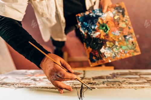 Preview: Old man artist painting oils in his studio.