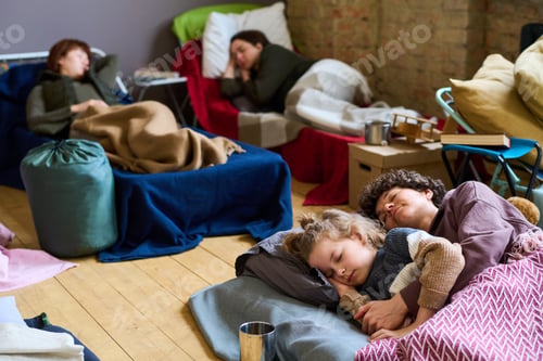 Preview: Young peaceful woman and her cute son sleeping on mattress on the floor