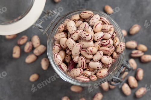 Preview: Glass jar full of dried pinto beans on gray top view, copy space. Traditional Latin American legumes