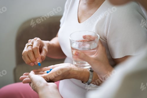 Preview: Grandma sits on the sofa at home, granddaughter giving medicine to granddaughter.