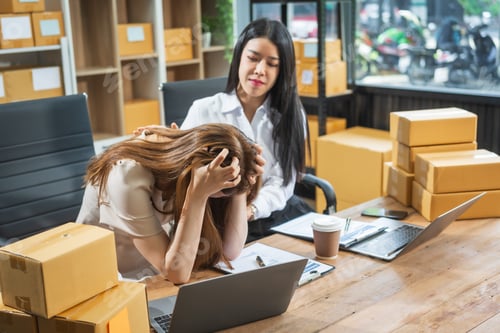 Preview: Two Asian business woman work at their desks, stressed by poor sales not reaching targets.Frequent