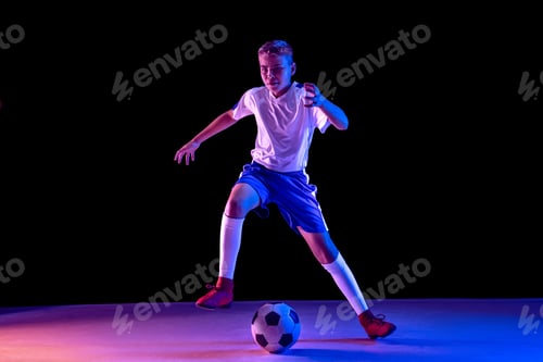 Preview: Young boy as a soccer or football player on dark studio background