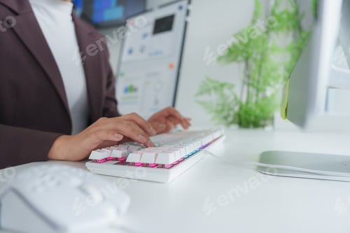 Preview: Businesswoman working on computer with charts in background at modern office desk