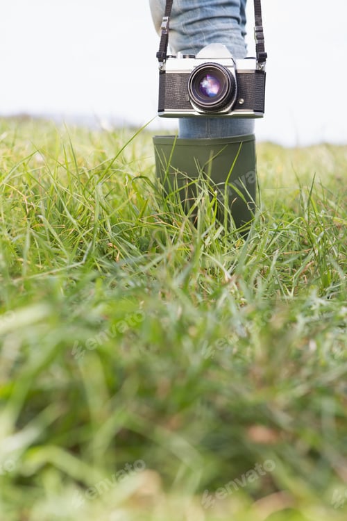Preview: Woman in the park holding retro camera on a sunny day