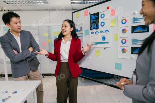 Preview: Asian businesswoman leading presentation with charts and pie graphs on whiteboard