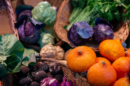 Preview: High angle closeup shot of different vegetables in straw baskets in a market