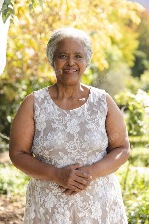 Preview: Portrait of happy senior biracial woman smiling in sunny garden at home