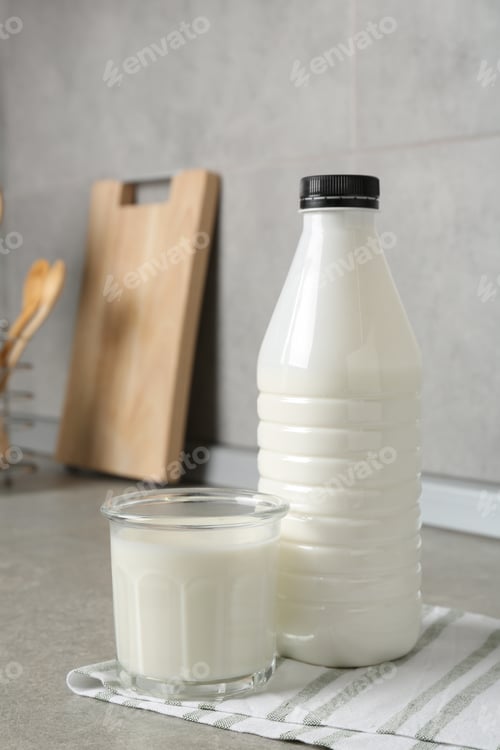 Preview: Dairy products. Fresh milk in glass and bottle on gray textured table indoors