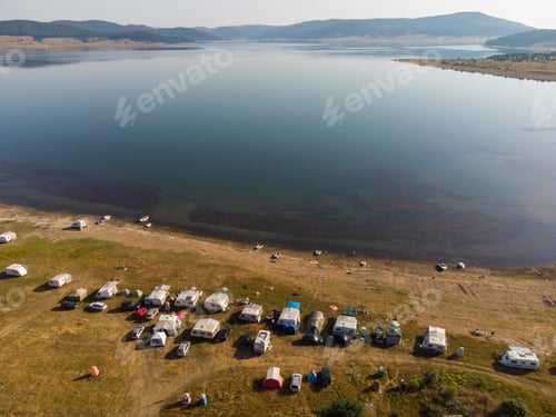 Preview: Aerial view of a campers van parked on a beach, mountain range landscape