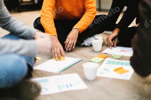 Preview: details on hands of people sitting on floor and discussing strategy and ideas