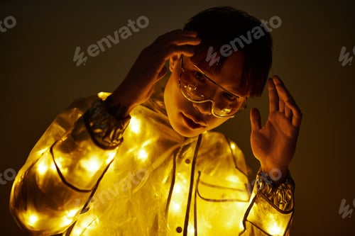 Preview: Young stylish Asian man adorned in glowing lights posing in an artistic atmosphere